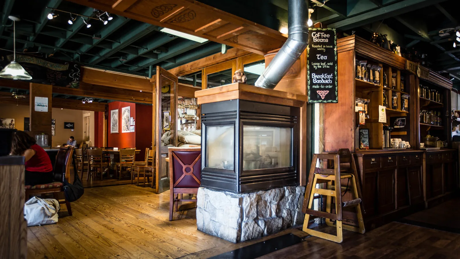 Interior de la cafetería con estanterías de madera y mesas